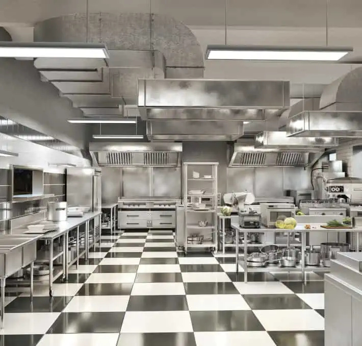 A commercial kitchen with stainless steel appliances, countertops, and ventilation hoods, featuring black and white checkered flooring.